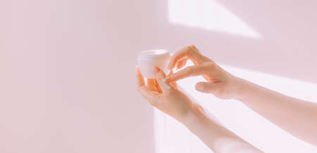 Women's hands hold a cosmetic copy space cream. An article about care cosmetics. hand cream. face cream.の写真素材