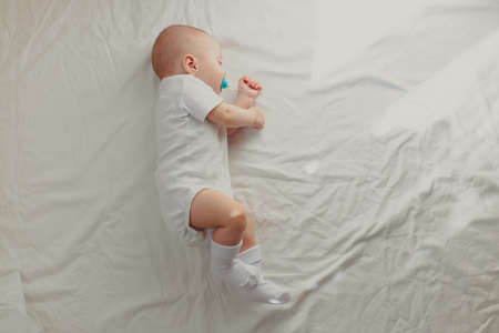The baby is lying in his crib and looking at the camera. A happy child. children's article. copy spaceの写真素材