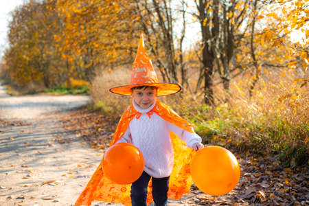 Portrait of a boy in Halloween clothes with pumpkin balloons on the street . A traditional holiday. October 31.の写真素材
