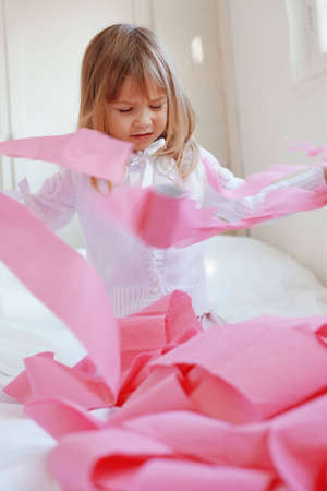 Portrait of child playing with pink toilet paperの写真素材