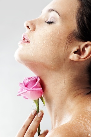 Studio portrait of sensual beautiful woman with rose and water droplets on her faceの写真素材