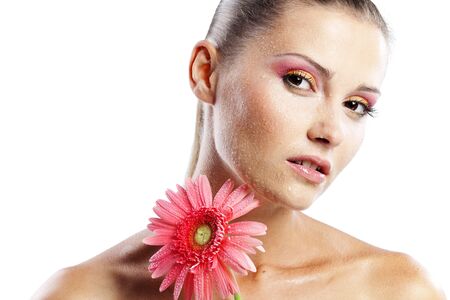 Portrait of beautiful female holding pink daisy with water drops on faceの写真素材