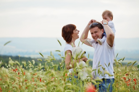 Happy young family baby resting in beautieful field of poppiesの写真素材