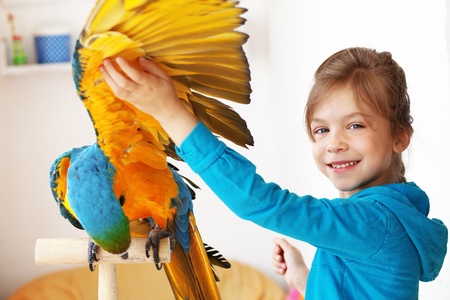 Portrait of a kid girl with her domestic ara parrotの写真素材