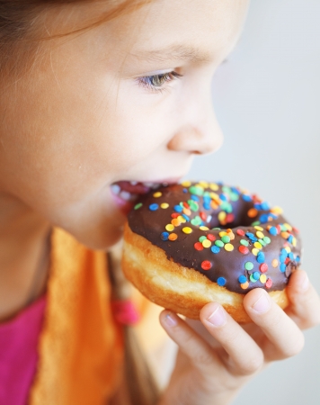 Cute kid girl eating sweet donutsの写真素材