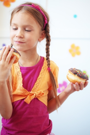 Cute kid girl eating sweet donutsの写真素材