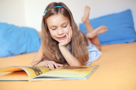 Portrait of 6 years old child reading book at homeの写真素材