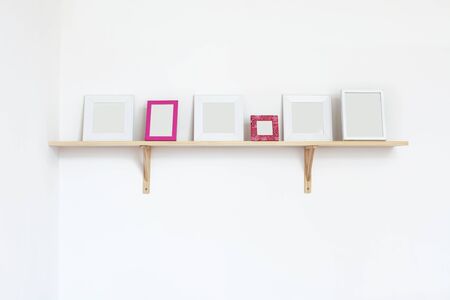 Simple blank photo frames on a shelf over white wallの写真素材