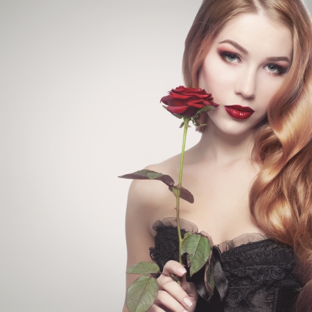 Portrait of a beuatiful young girl holding a red roseの写真素材