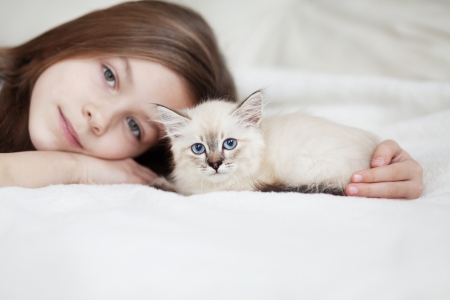 Home portrait of adorable child with small kitten resting on a soft sofaの写真素材