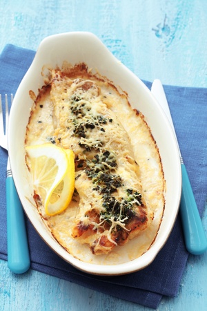 Cooked fish with spinach in baking dish on blue wooden tableの写真素材