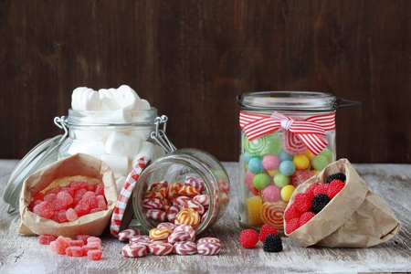 Sweet sugar candies in glass jars on brown vintage wooden backgroundの写真素材