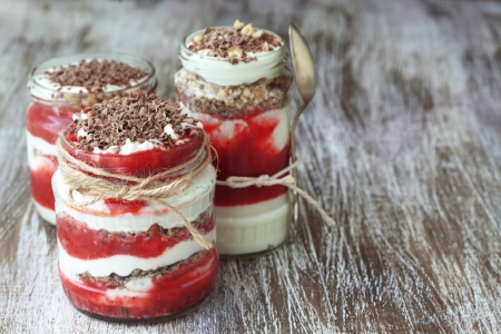 Layered dessert with fruits, nuts and cream cheese in glass jar, selective focusの写真素材