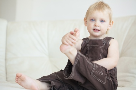 Picture of a baby sitting on a sofa at homeの写真素材