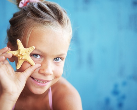 Child holding seashell on blue backgroundの写真素材