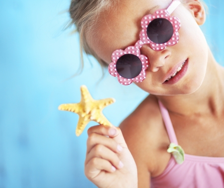 Child holding seashell on blue backgroundの写真素材