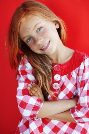 Cute redheaded child on red backgroundの写真素材