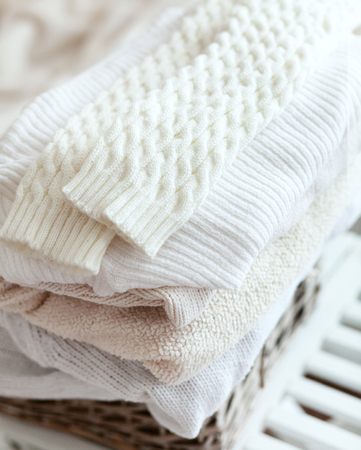 Stack of cozy knitted sweaters in wicker backet