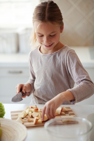 Portrait of a 7 years old girl making salad in kitchen at homeの写真素材