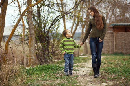 Young mother walking with her little son outdoors in autumnの写真素材