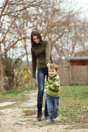 Young mother walking with her little son outdoors in autumnの写真素材