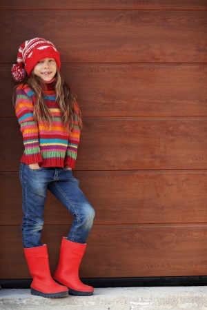Cute little girl wearing knit winter clothes posing over wooden の写真素材
