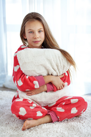 Portrait of child in soft warm pajamas sitting on the carpet at homeの写真素材