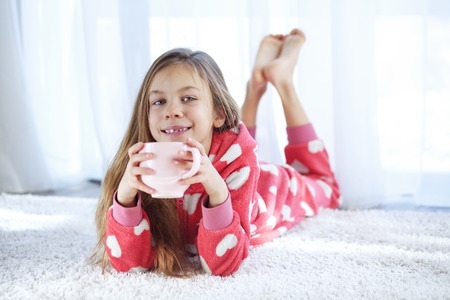 Portrait of child in soft warm pajamas lying down on the carpet at homeの写真素材