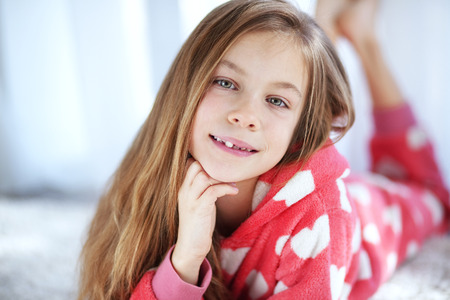 Portrait of child in soft warm pajamas lying down on the carpet at home