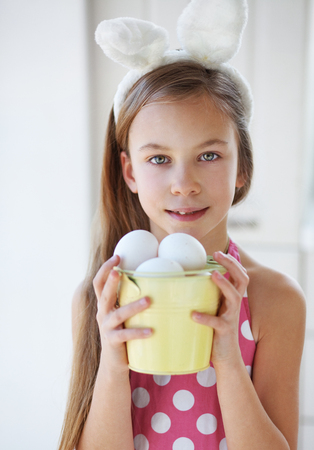 Portrait of a pretty little girl wearing bunny ears holding Easter eggsの写真素材