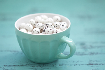 Easter eggs in a cup closeup ob vintage aqua blue wooden background, shallow focusの写真素材