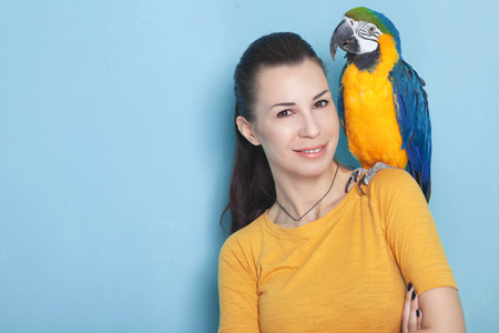 Portrait of a young woman with her domestic ara parrot