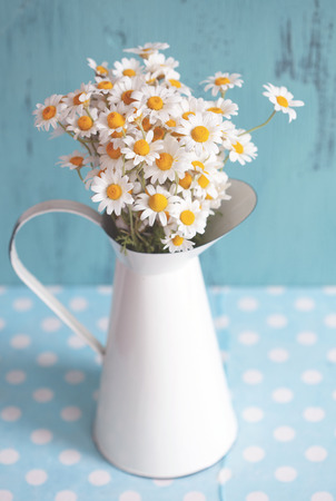 Bouquet of simple chamomiles in vintage pitcher on blue polka dot napkinの写真素材