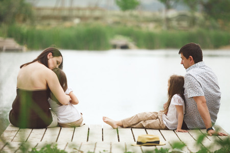Young family with children resting near pondの写真素材
