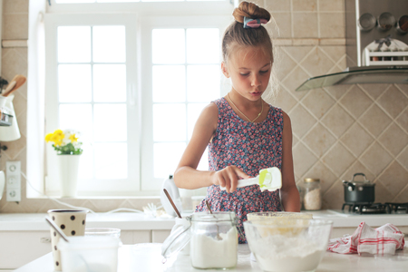 7 years old school girl cooking at the kitchen, casual lifestyle photo seriesの写真素材
