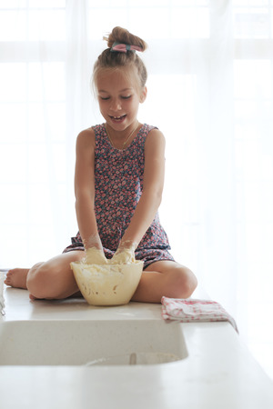 7 years old school girl cooking at the kitchen, casual lifestyle photo seriesの写真素材