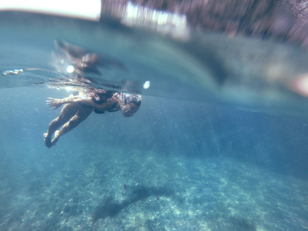 Underwater photo of a human diving in blue sea water