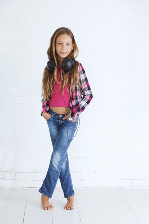 8-9 years old stylish teen girl with black headphones posing on white backgroundの写真素材