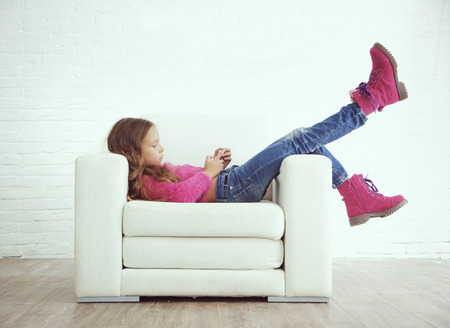 Cute pre-teen girl wearing fashion winter clothes posing in white interiorの写真素材
