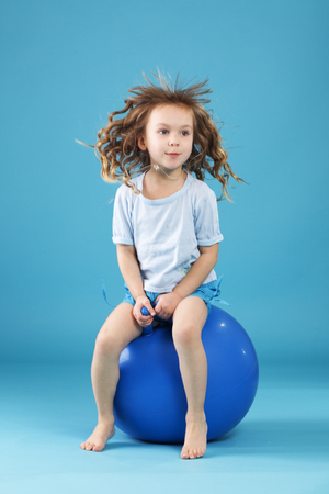 5 years old child playing with fitball l on blue studio backgroundの写真素材