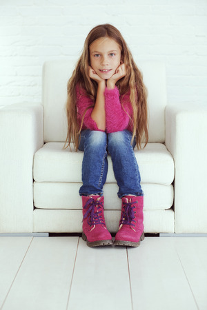 Cute pre-teen girl wearing fashion winter clothes posing in white interiorの写真素材