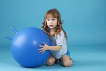 5 years old child playing with fitball l on blue studio backgroundの写真素材