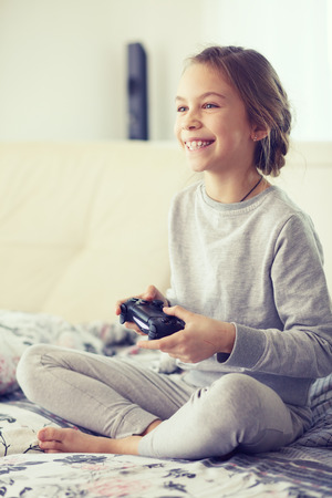 Child playing video game on tv in morning at parent's bedroom at homeの写真素材