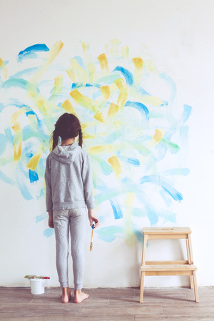 8 years old girl painting the wall at home の写真素材