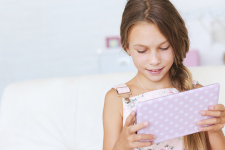 Preteen school girl of 8-9 years old playing on tablet pc at homeの写真素材