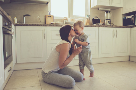 Mom with her 2 years old child cooking holiday pie in the kitchen to Mothers day, casual lifestyle photo series in real life interiorの写真素材