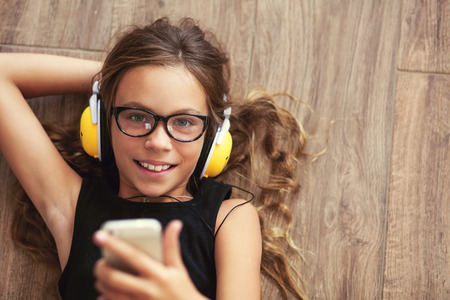9 years old child is lying down on the floor and listening to music, top view pointの写真素材