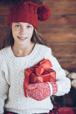 Child giving a Christmas present on rustic wooden background, farmhouse interior.の写真素材
