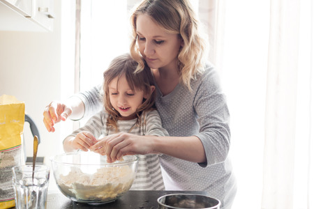 Mom with her 5 years old child cooking holiday pie in the kitchen to Mothers day, casual still life...