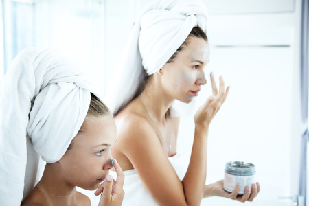 Mother and tween daughter make a clay facial mask, family scin care in the bathroomの写真素材